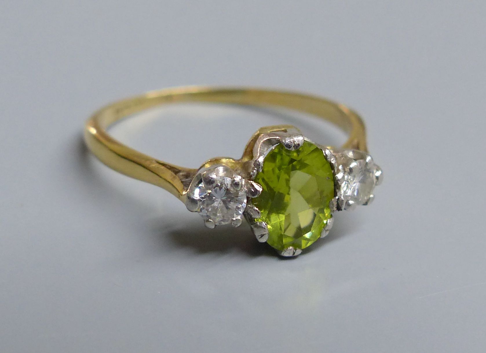 An 18ct and plat. peridot and diamond set three stone ring, size N, gross 2.5 grams.